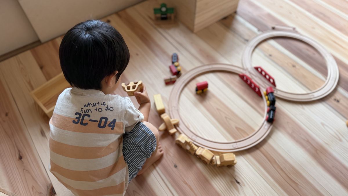 A child playing with wooden toys spread across the cedar floor