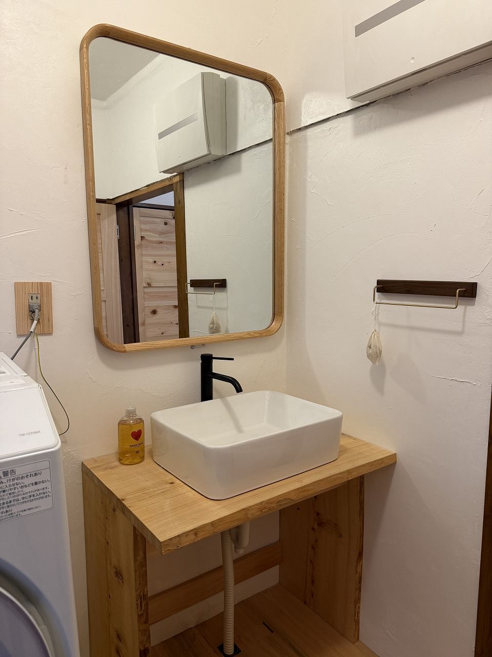 The washstand, with a wood-framed mirror and a solid-wood counter